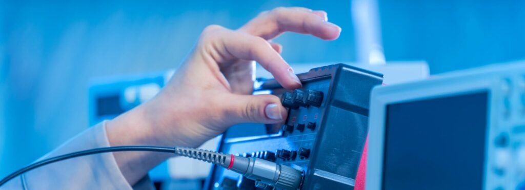 Hand dreht einen Knopf an einem Messwerkzeug in einem Elektrolabor
